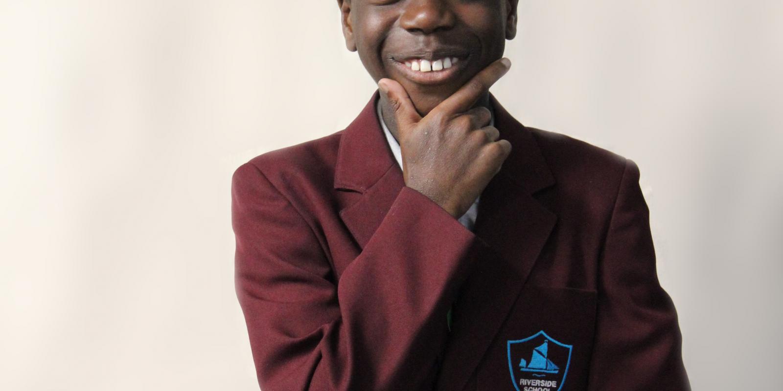 school boy smiling cheekily with hand up to chin