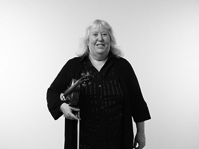 Susan Carvell holding a violin and smiling to camera