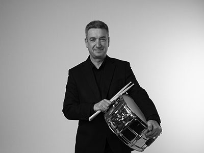 Giles Harrison holding a drum and smiling to camera