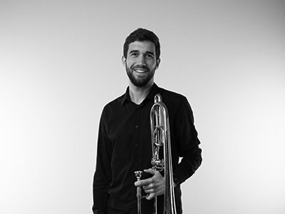 Joe Arnold holding a trombone and smiling to camera