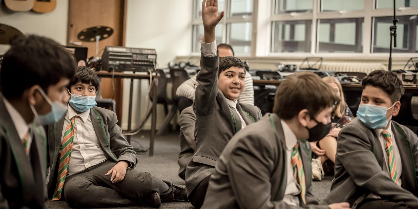 A pupil eagerly raises their hand