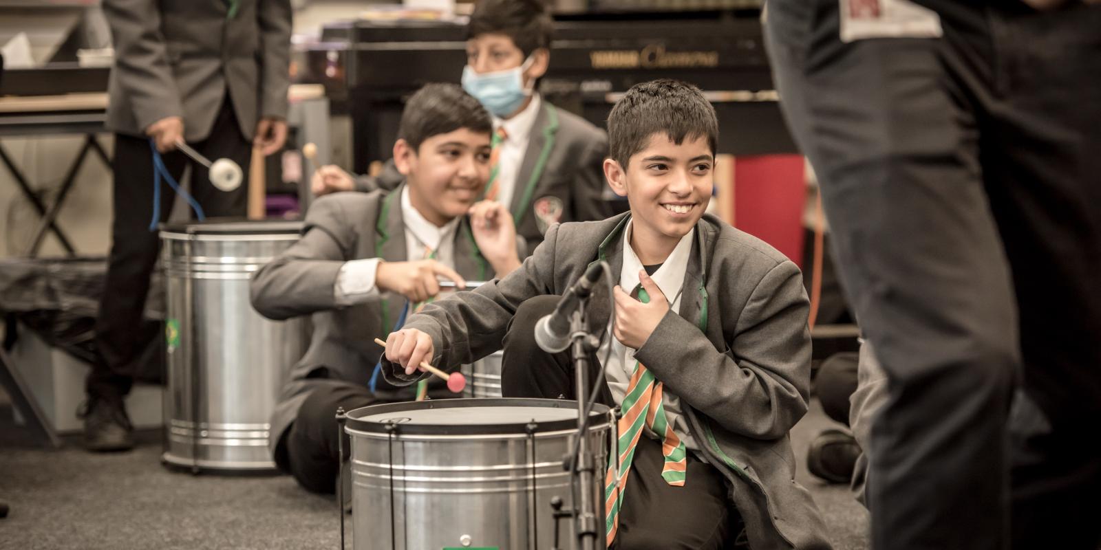 A smiling pupil hits a drum