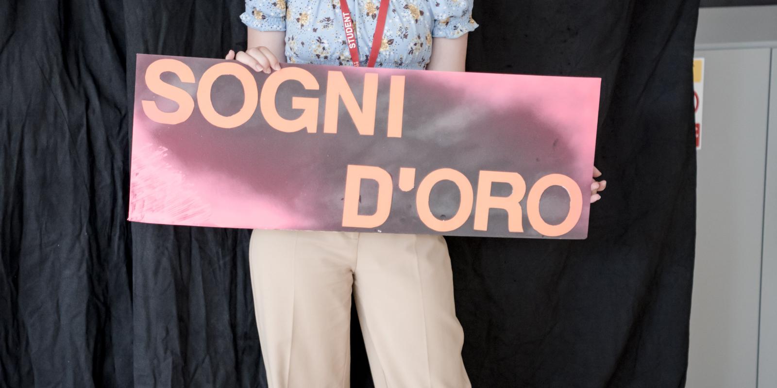 Young Girl holding a sign reading Sogni D'oro