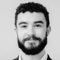Black and white headshot of Ossian Huskinson, looking directly to camera