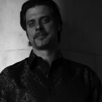 Black and white headshot of John Relyea looking to camera