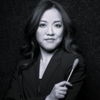 Black and white headshot of Erina Yashima looking at the camera and holding a conducting baton.