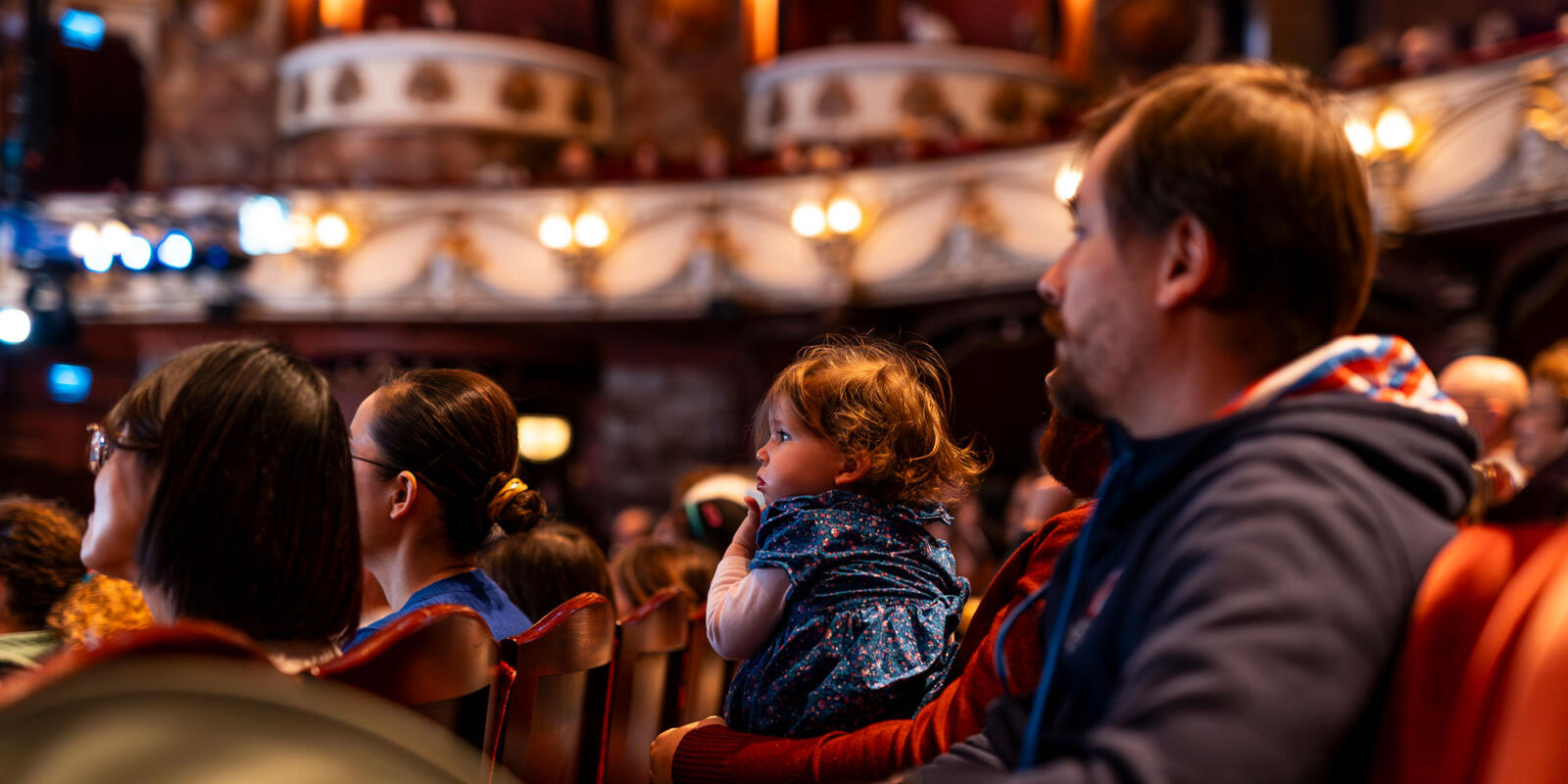 Baby in lap watching the stage of the London Coliseum during the Relaxed performance of ENO's Iolanthe---Wednesday 25 October 2023 © Lloyd Winters